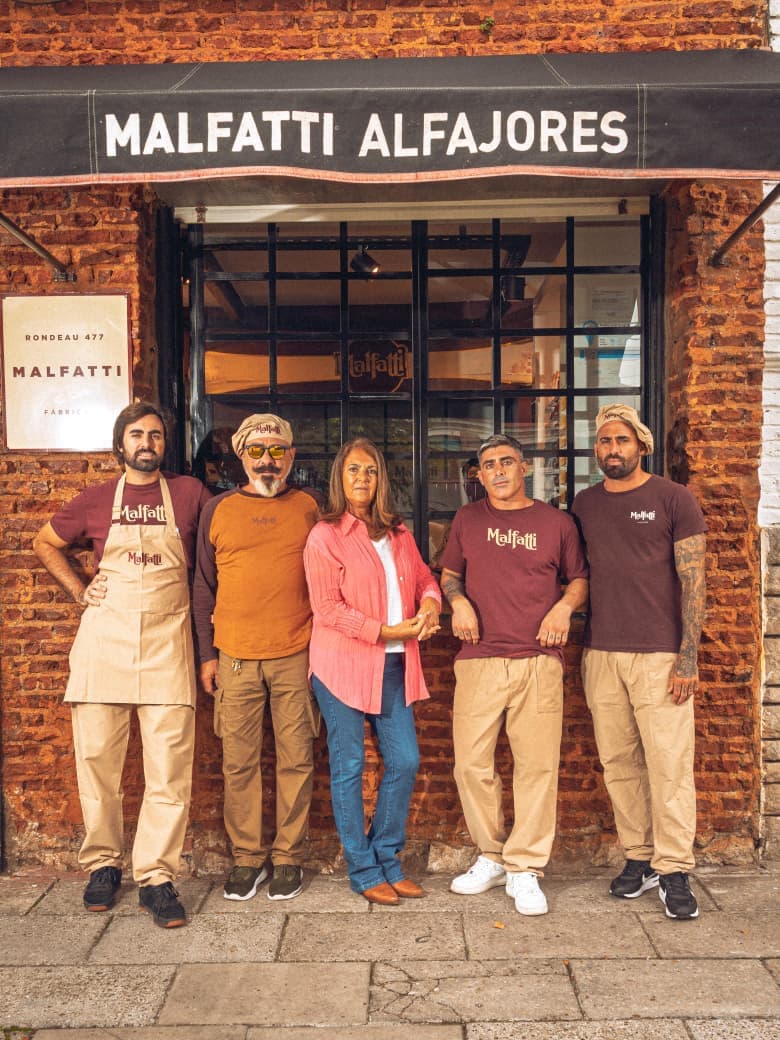 La familia Malfatti, cinco personas paradas frente a la fábrica de Rondeau 477, bajo el toldo que dice Malfatti Alfajores.