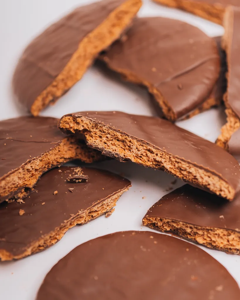 Galletitas Malfatti bañadas en chocolate, enteras y partidas, sobre un fondo blanco.