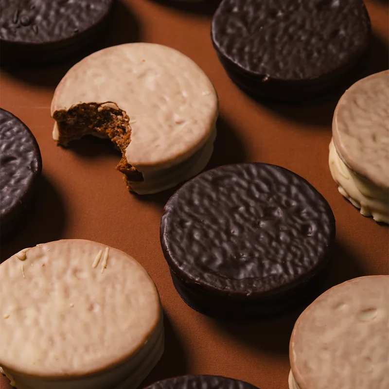 Alfajores Malfatti bañados en chocolate semiamargo y en chocolate blanco, vistos desde arriba.
